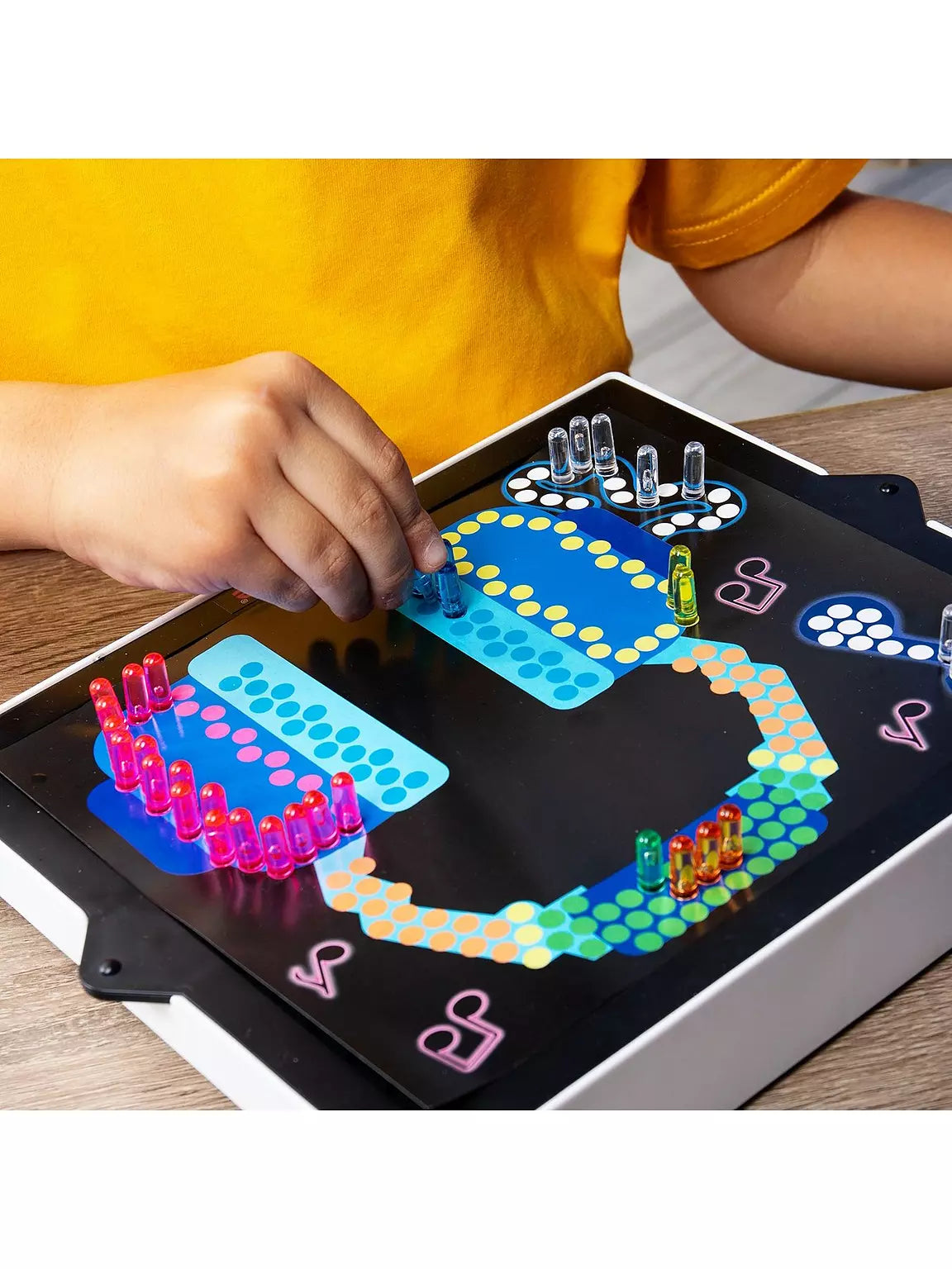Child inserts colorful translucent pegs into a light-up board to create a glowing headphone and music note design.