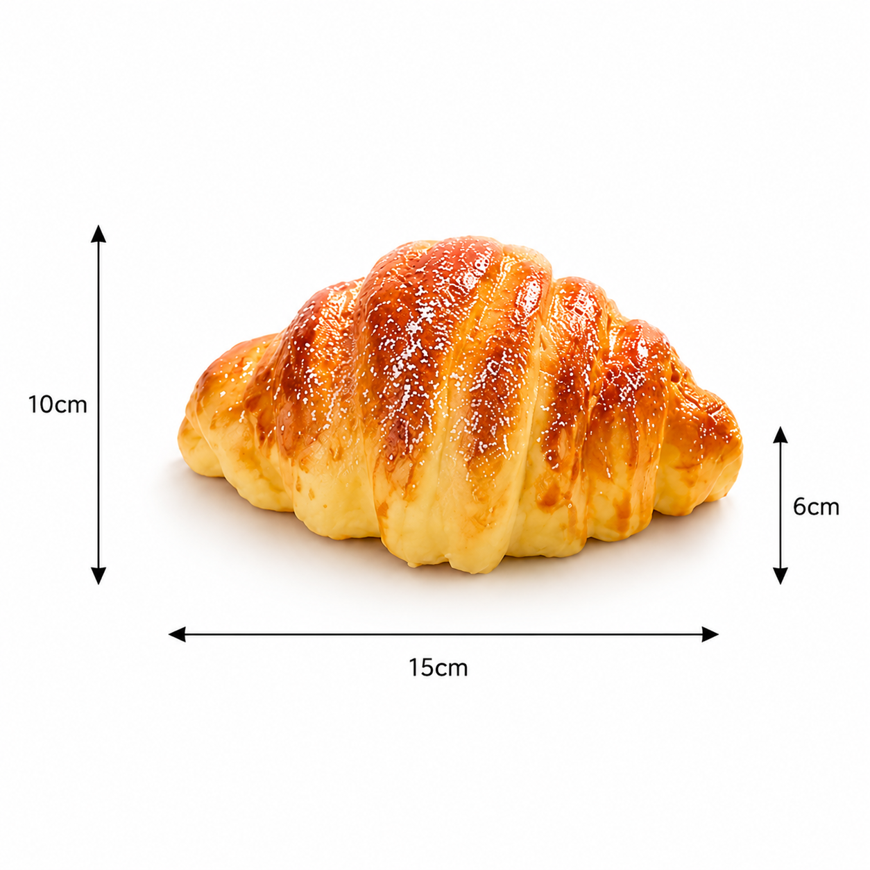 Realistic golden-brown croissant toy with white dusting and dimension lines showing its 15cm x 10cm x 6cm measurements.