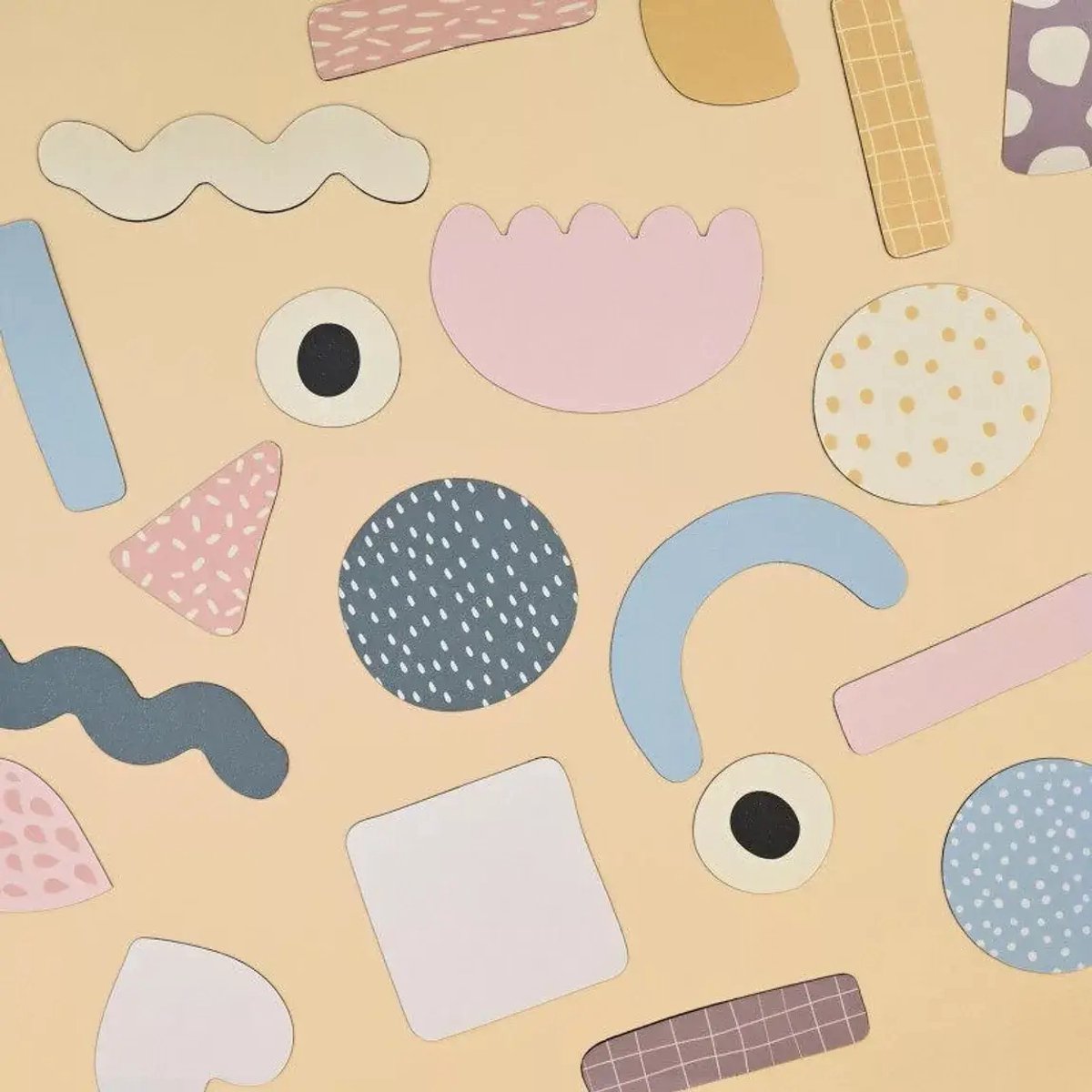 Abstract pastel magnetic shapes with dots and stripes scattered across a solid beige magnetic board.