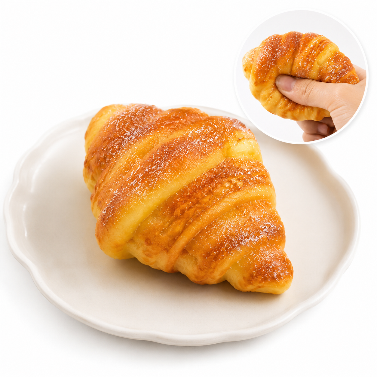 Realistic golden croissant toy on a white plate; inset shows a hand squeezing the soft, powdered squishy.
