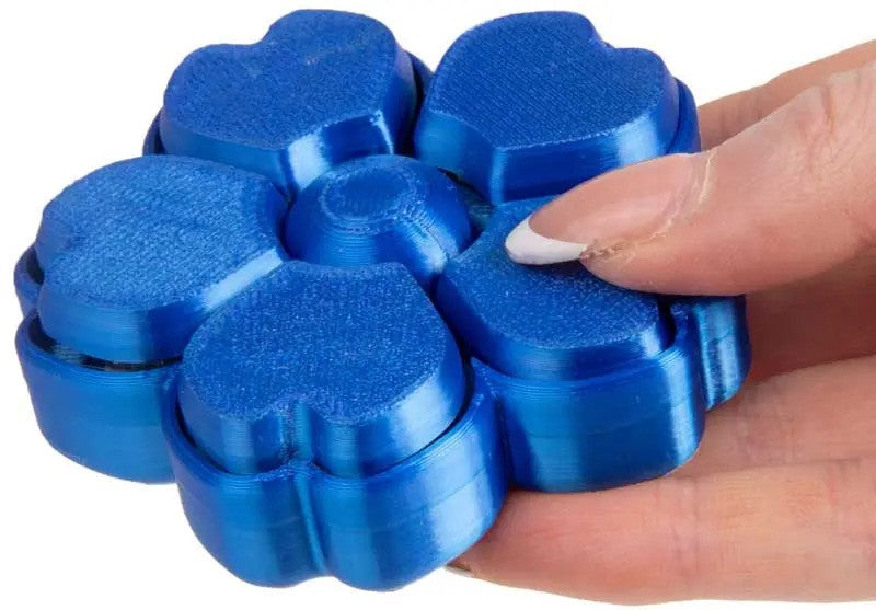Metallic blue 3D-printed flower fidget toy with five rotating heart-shaped petals held in a hand.