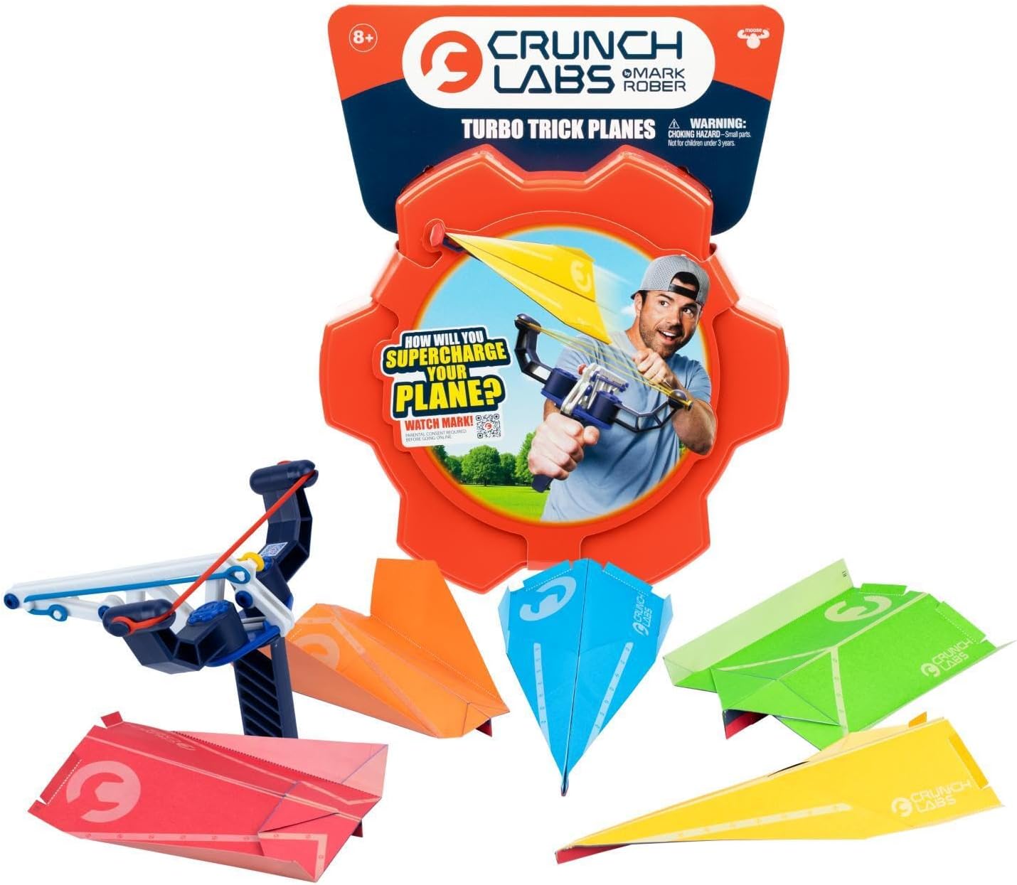 A handheld paper plane launcher next to five colored paper planes and an orange hexagonal storage case.
