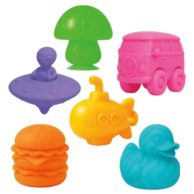 Six colorful squishy toys: green mushroom, pink van, purple alien saucer, yellow submarine, orange burger, and blue duck.