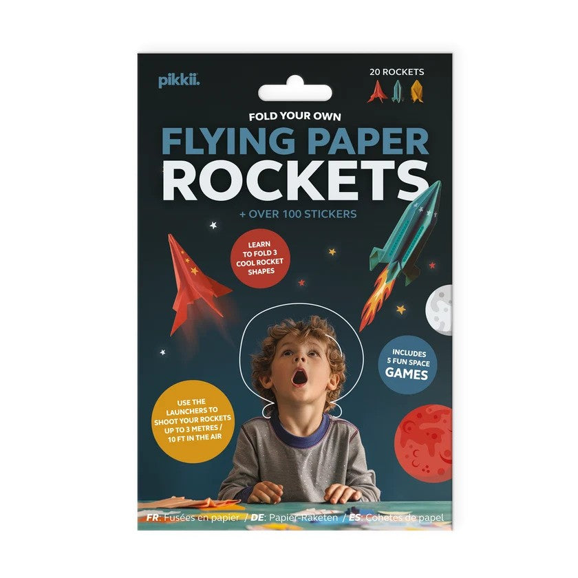 Packaging for a DIY paper rocket kit showing a child gazing at flying paper rockets, stars, and planets.