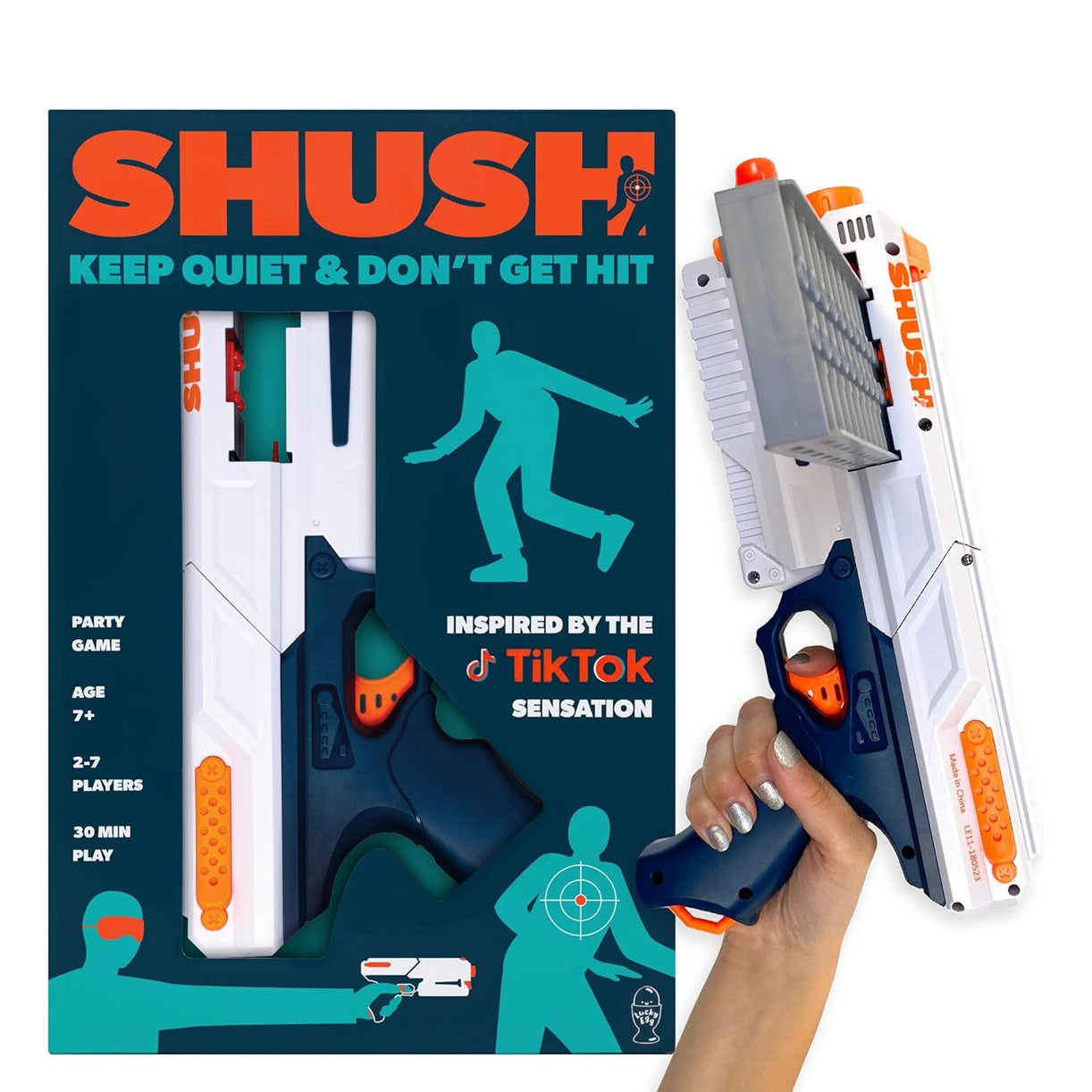 A white and navy blue SHUSH toy blaster with a vertical magazine held in a hand next to its teal and orange packaging.