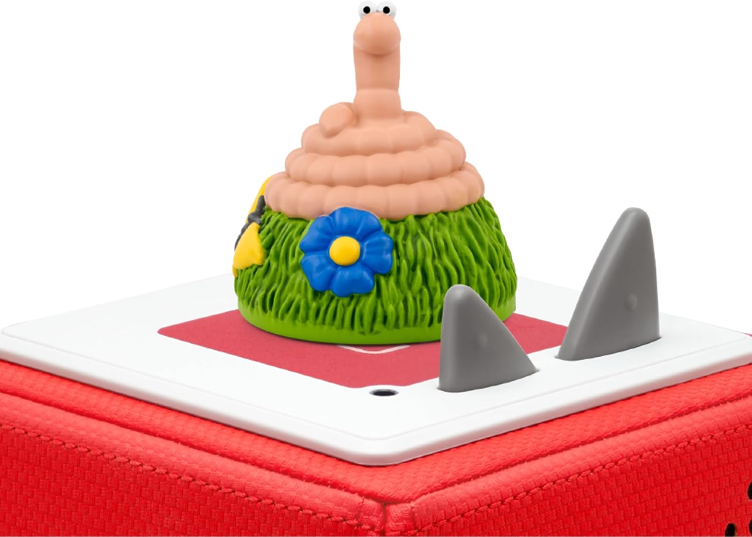 Red Toniebox audio player with a pink coiled worm figurine on a green base with a blue flower.