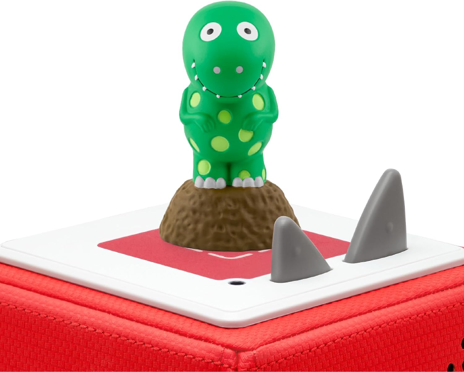 Green Dorothy the Dinosaur character toy with yellow spots standing on a red Toniebox audio player.