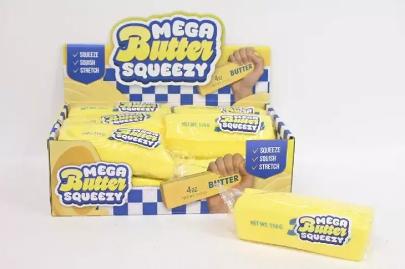 A yellow rectangular squishy toy shaped like a stick of butter in clear plastic wrapping next to its display box.