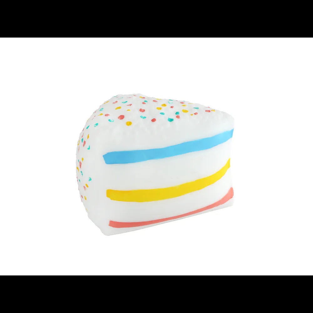 A white toy cake slice with multi-colored sprinkles and horizontal stripes of blue, yellow, and pink on its side.