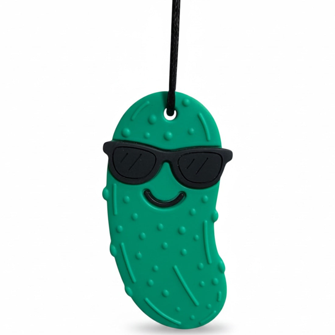 A green silicone pickle-shaped chew pendant wearing black sunglasses and a smiley face, hanging on a black cord.