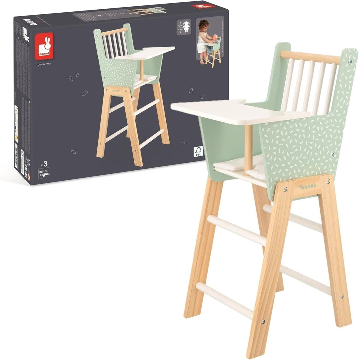 Mint green and white wooden doll high chair standing next to its dark grey Janod packaging showing a child playing.