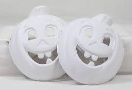 Two white unpainted ceramic pumpkin masks with cutout eyes and smiling toothy mouths.