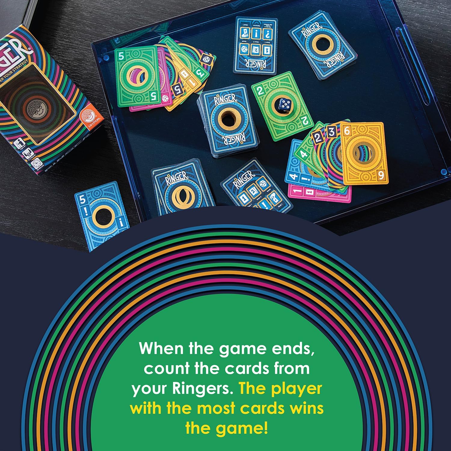 Colorful circular-patterned cards, a die, and box for Ringer game in a blue tray with scoring instructions.